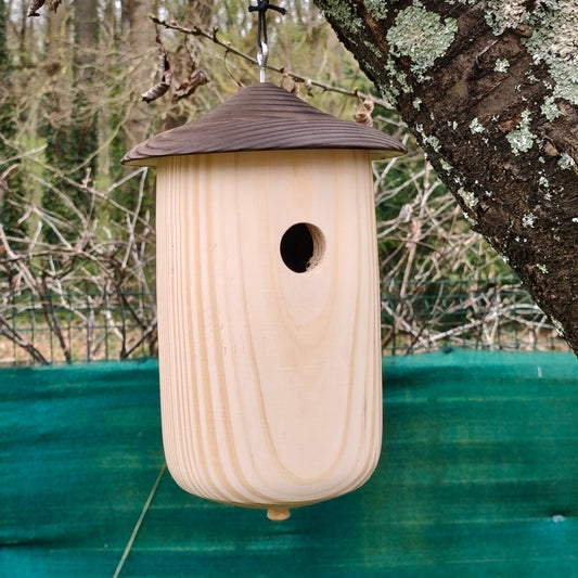 image d un nichoir en bois tourne avec toit en bois brule suspendu dans un arre